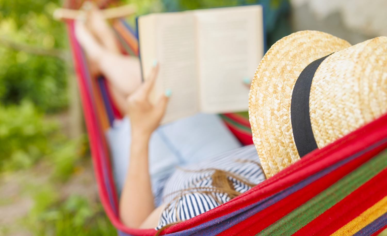 A highly sensitive person reading a book and relaxing in a brightly colored hammock as a form of self care.