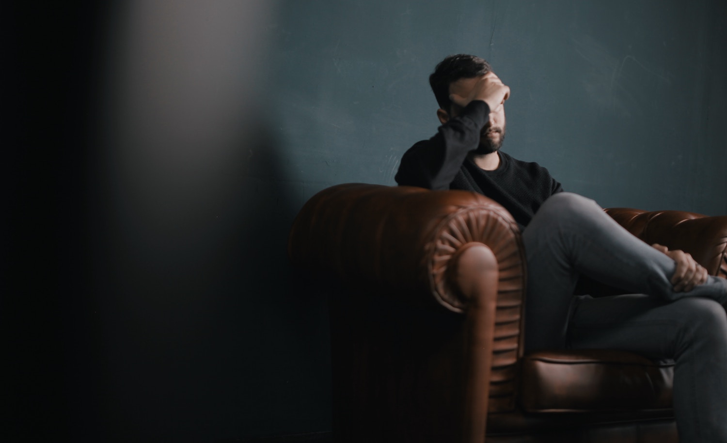 A highly sensitive man, seated, looking tired and dealing with overstimulation and intense emotions, as described in the book "The Highly Sensitive Man" by Tom Falkenstein.