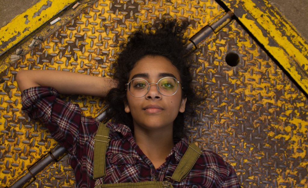 A woman dealing with her unhealthy perfectionism, lying down on a yellow floor.