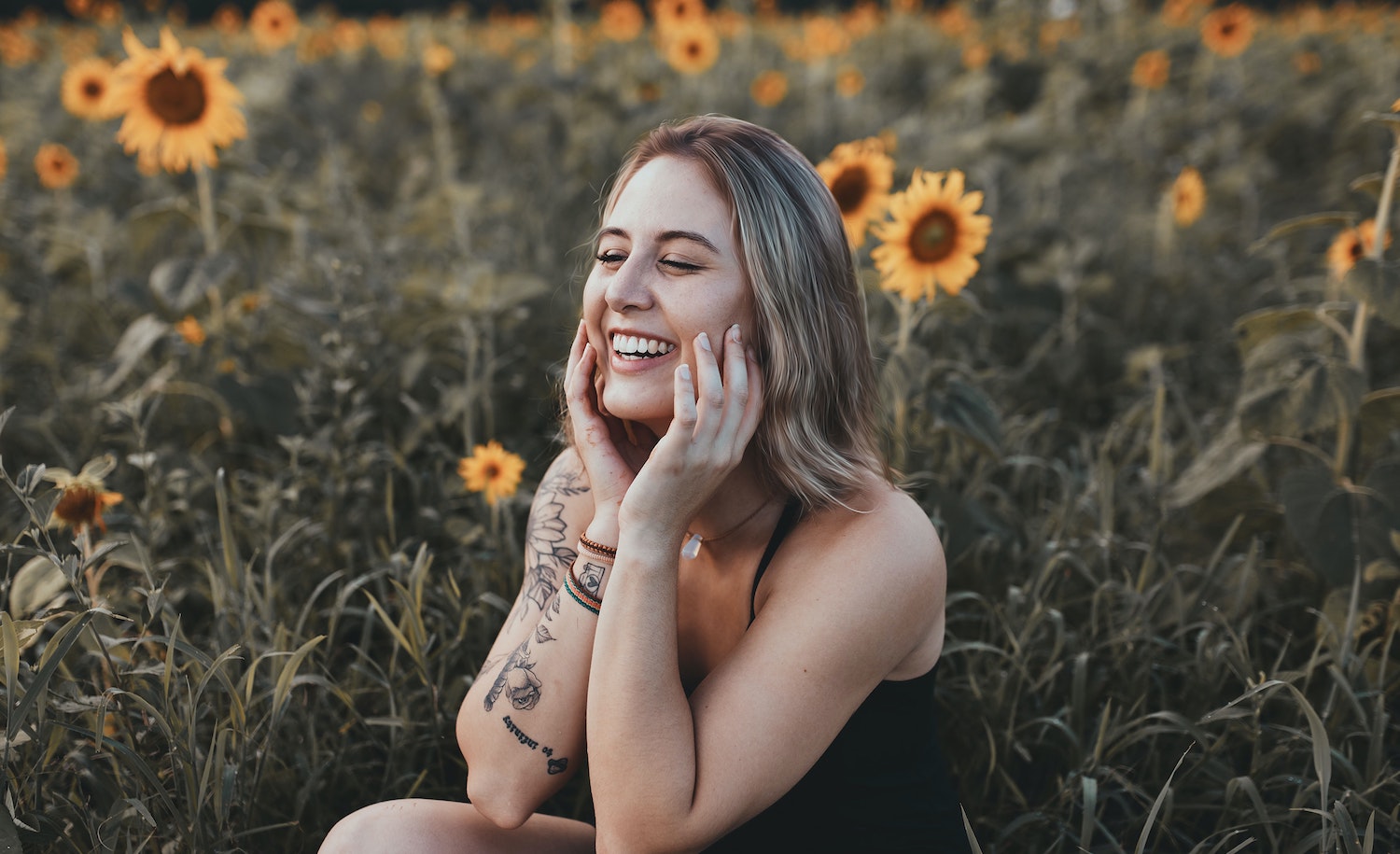 A sensitive person (woman) happy and smiling in a field of sunflowers