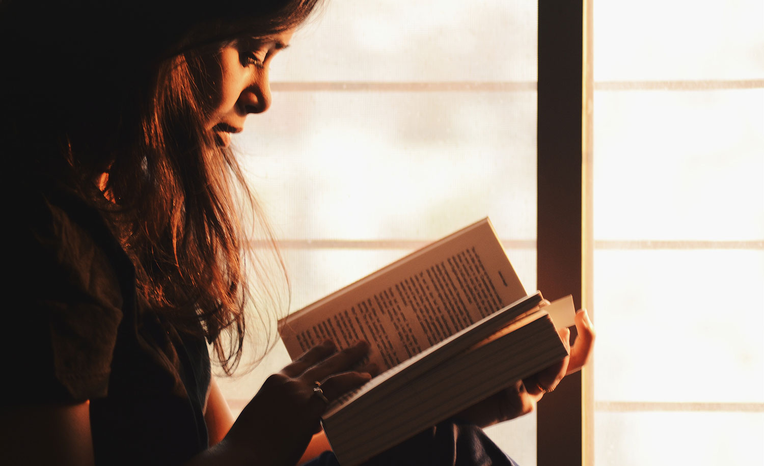 A highly sensitive person reads a book by the window.