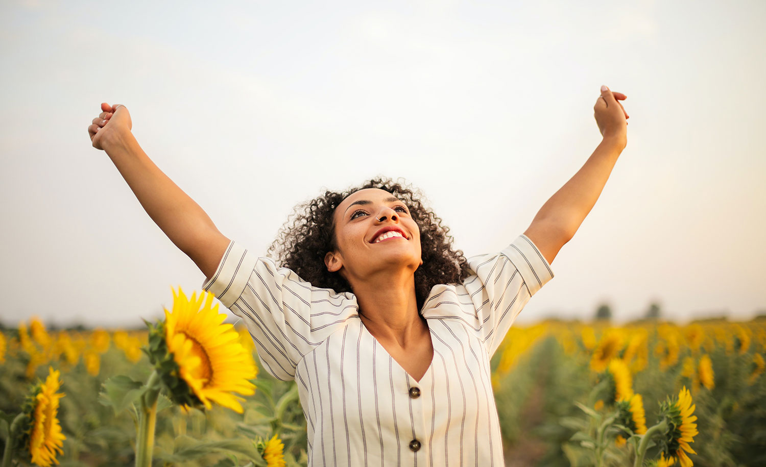 A happy highly sensitive woman in a field of sunflowers