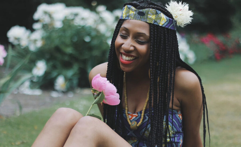 A happy woman looks at a flower.