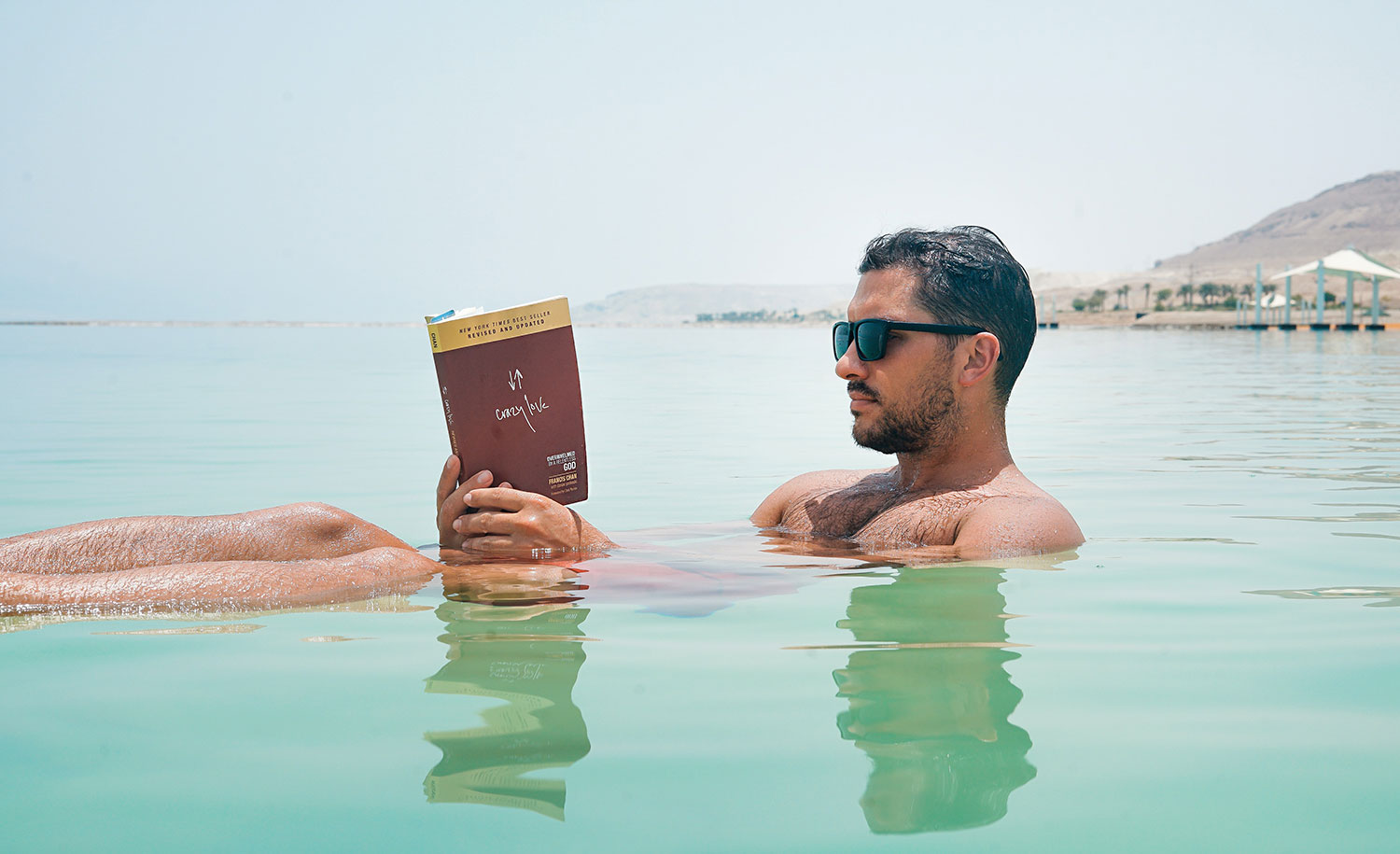 A highly sensitive male reads a book in a body of water