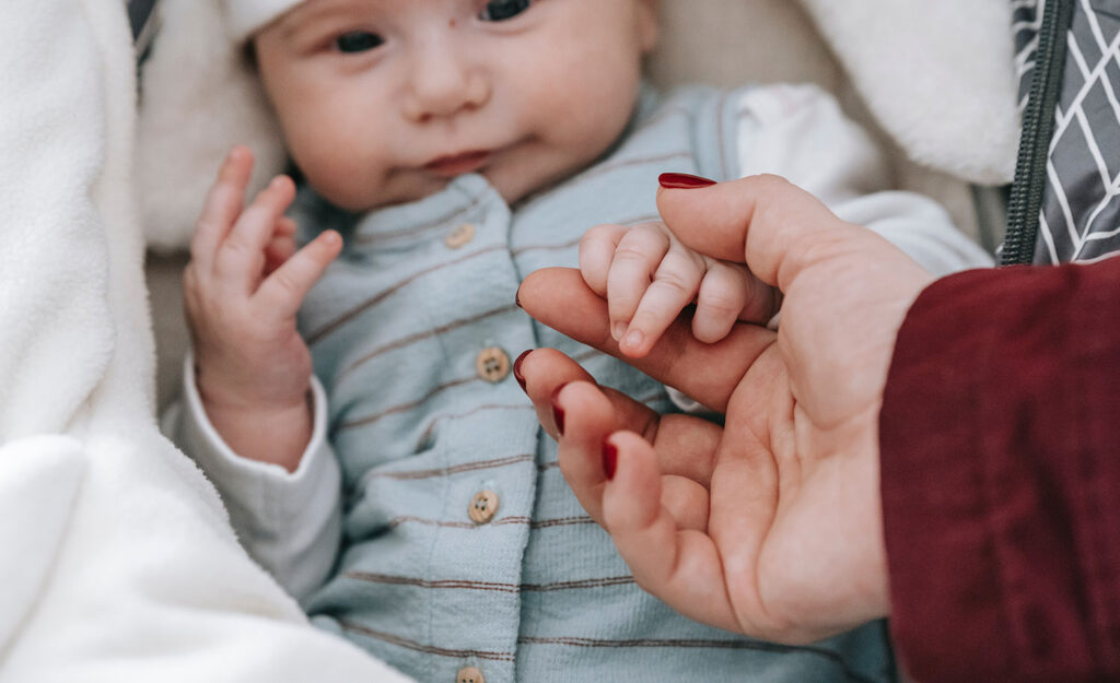 A highly sensitive parent holds their baby’s hand.