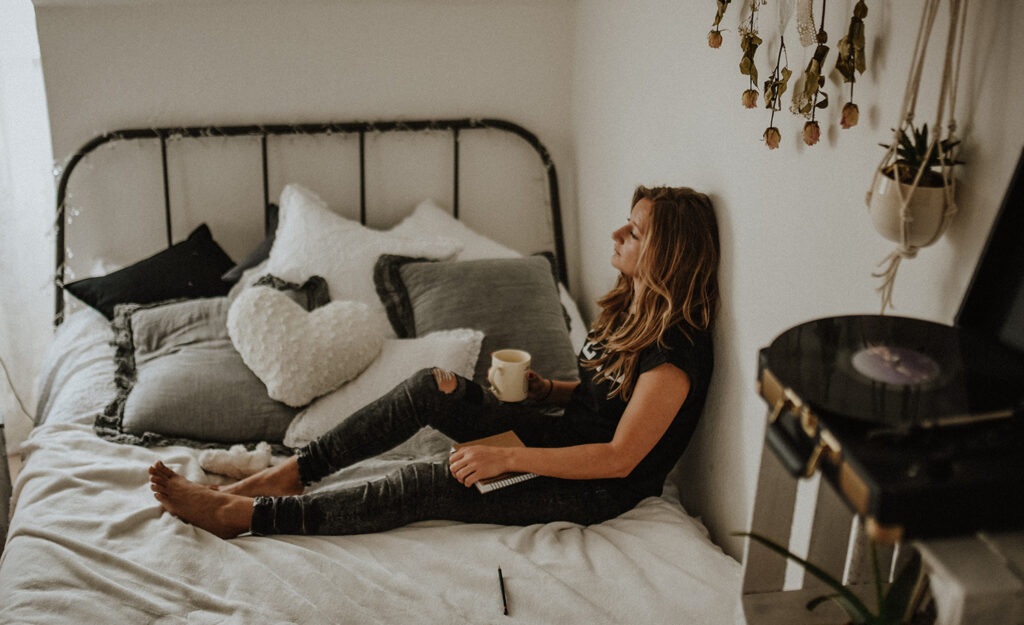 A highly sensitive woman sits in bed, forlorn