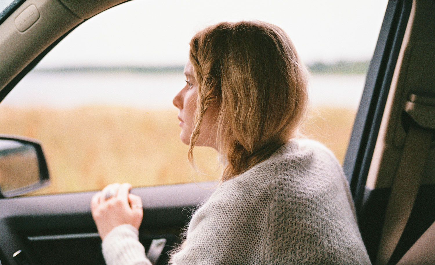 A pensive woman looks out a car window
