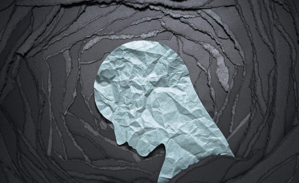 Silhouette of a highly sensitive person lowering his head as he struggles with work addiction